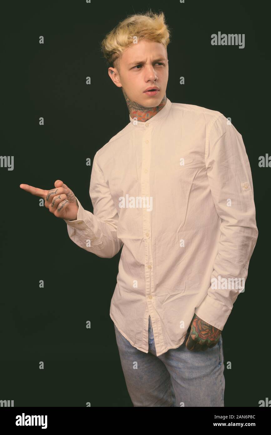 Beau jeune homme rebelle aux cheveux blonds sur fond noir Banque D'Images