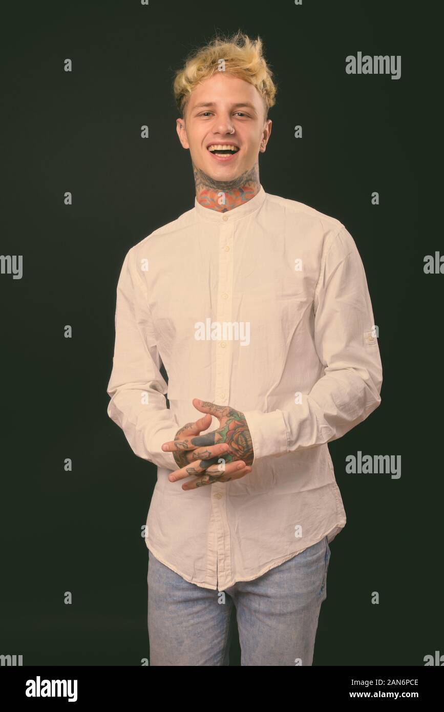 Beau jeune homme rebelle aux cheveux blonds sur fond noir Banque D'Images