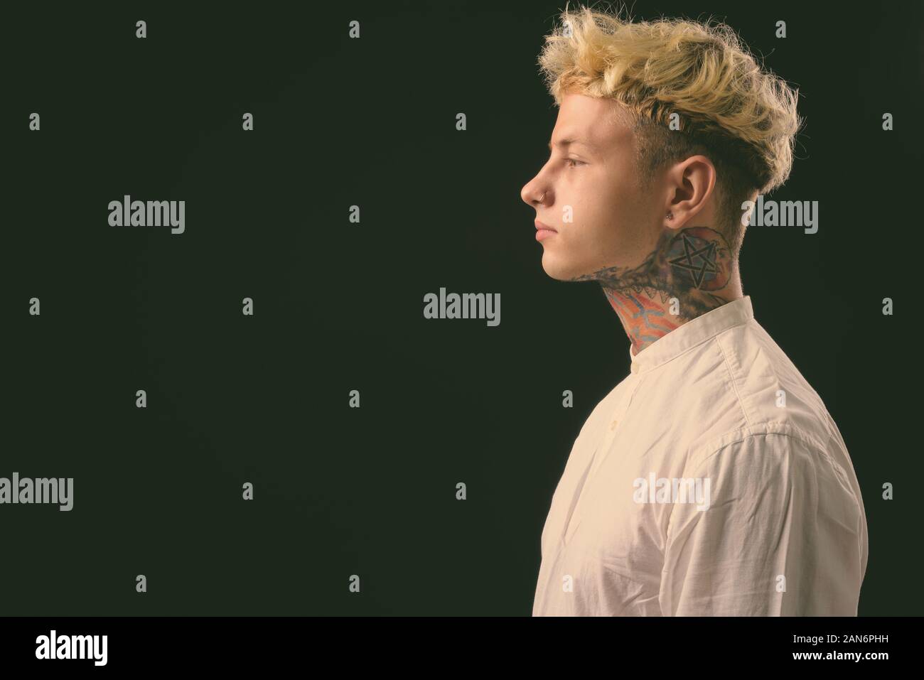 Beau jeune homme rebelle aux cheveux blonds sur fond noir Banque D'Images