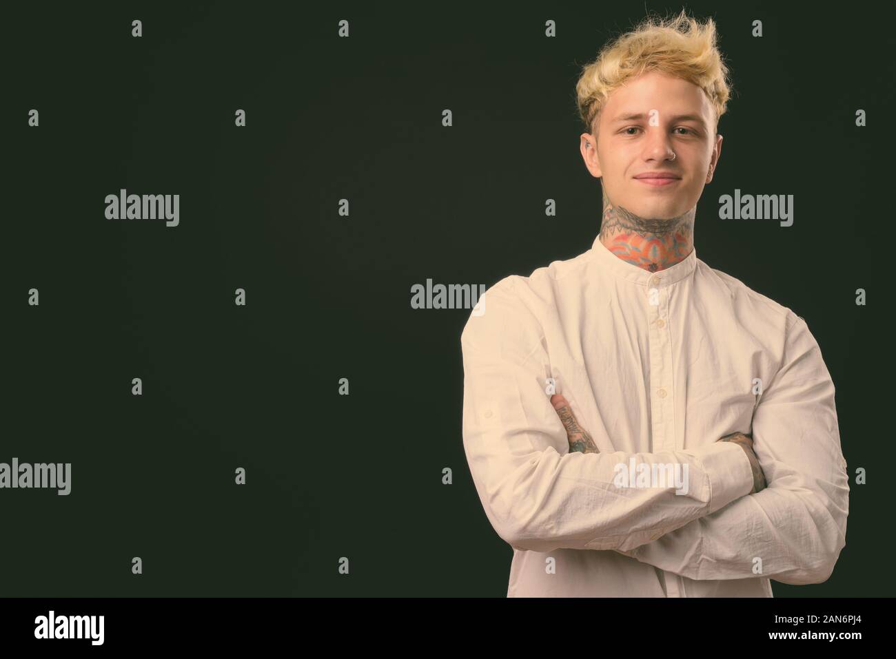 Beau jeune homme rebelle aux cheveux blonds sur fond noir Banque D'Images