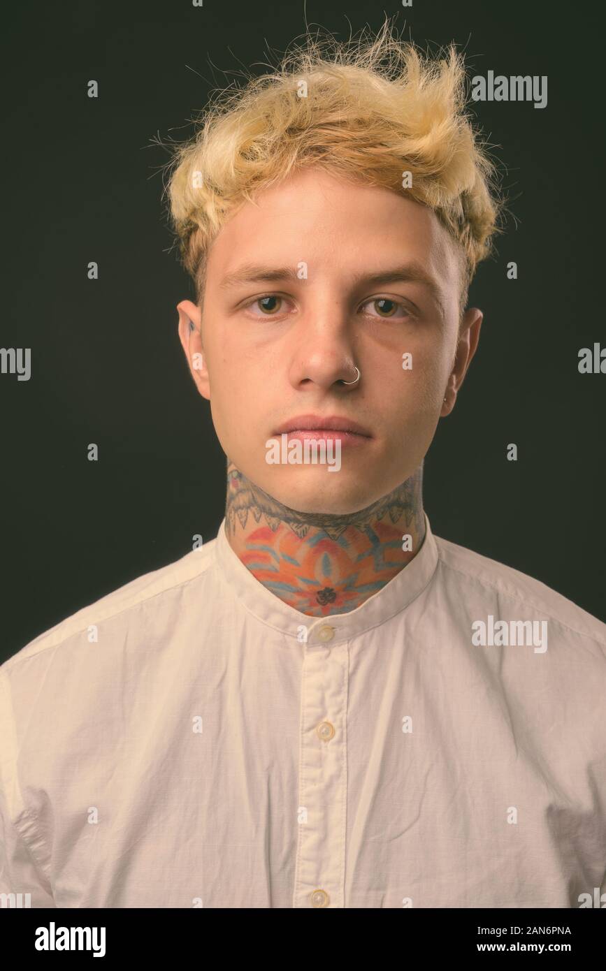 Beau jeune homme rebelle aux cheveux blonds sur fond noir Banque D'Images