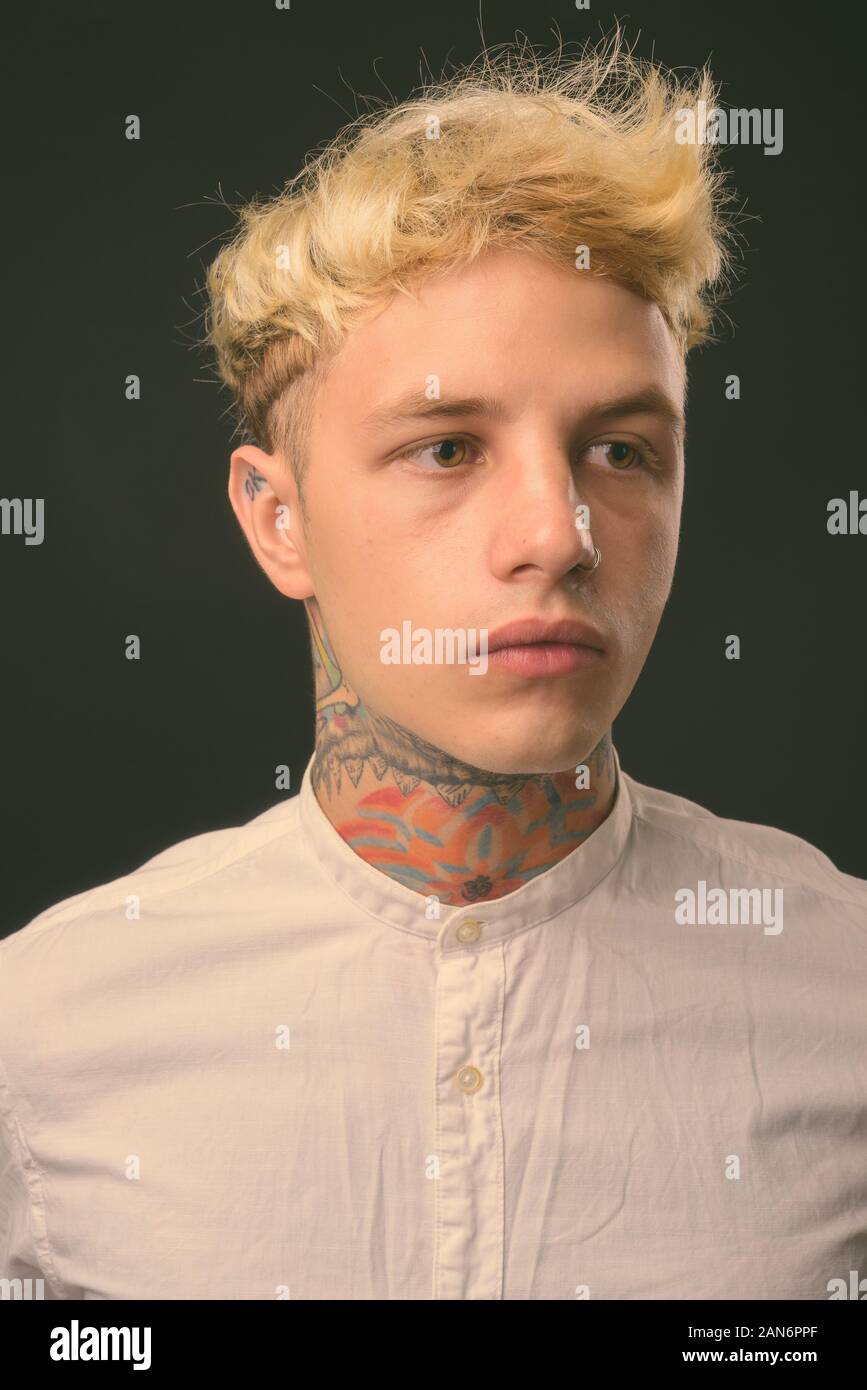 Beau jeune homme rebelle aux cheveux blonds sur fond noir Banque D'Images