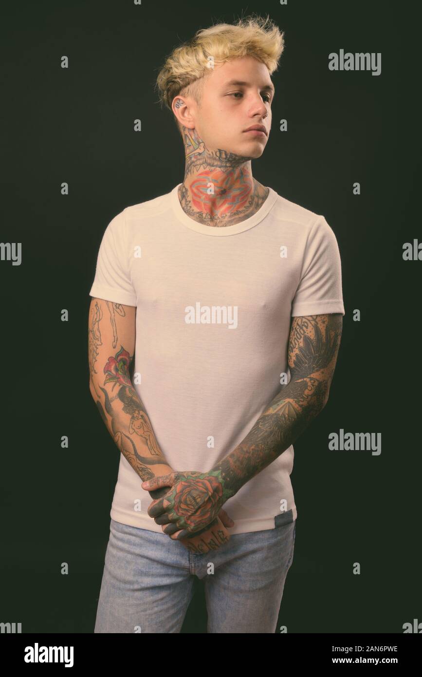 Beau jeune homme rebelle aux cheveux blonds sur fond noir Banque D'Images