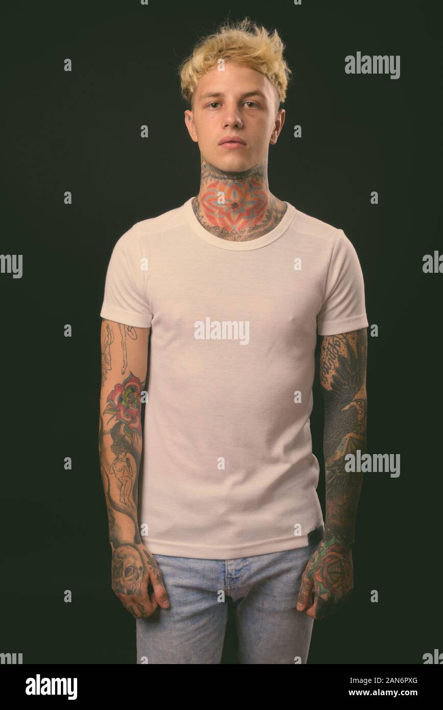 Beau jeune homme rebelle aux cheveux blonds sur fond noir Banque D'Images