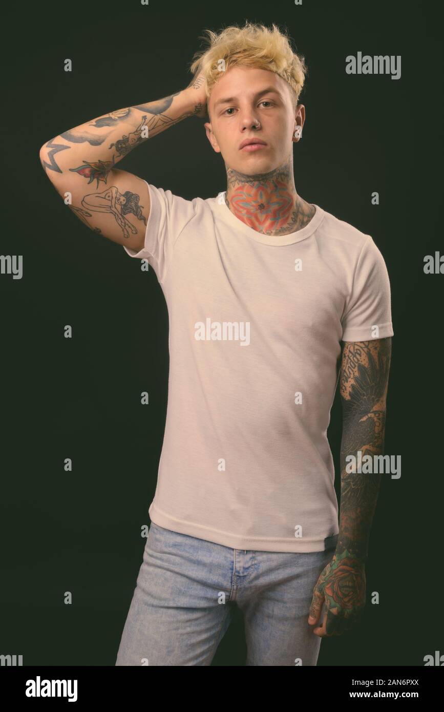 Beau jeune homme rebelle aux cheveux blonds sur fond noir Banque D'Images