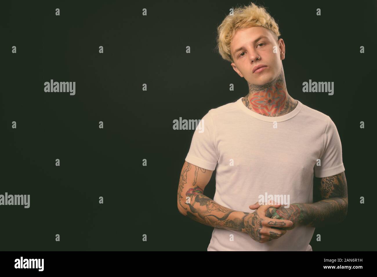 Beau jeune homme rebelle aux cheveux blonds sur fond noir Banque D'Images