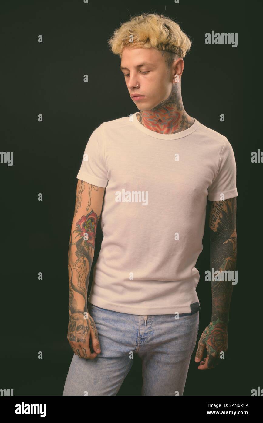 Beau jeune homme rebelle aux cheveux blonds sur fond noir Banque D'Images