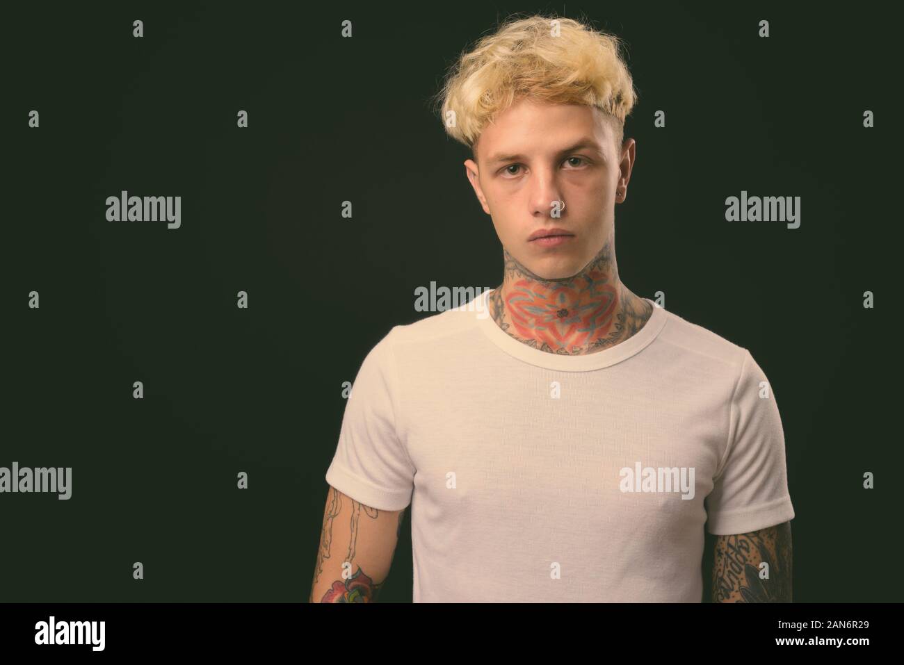 Beau jeune homme rebelle aux cheveux blonds sur fond noir Banque D'Images