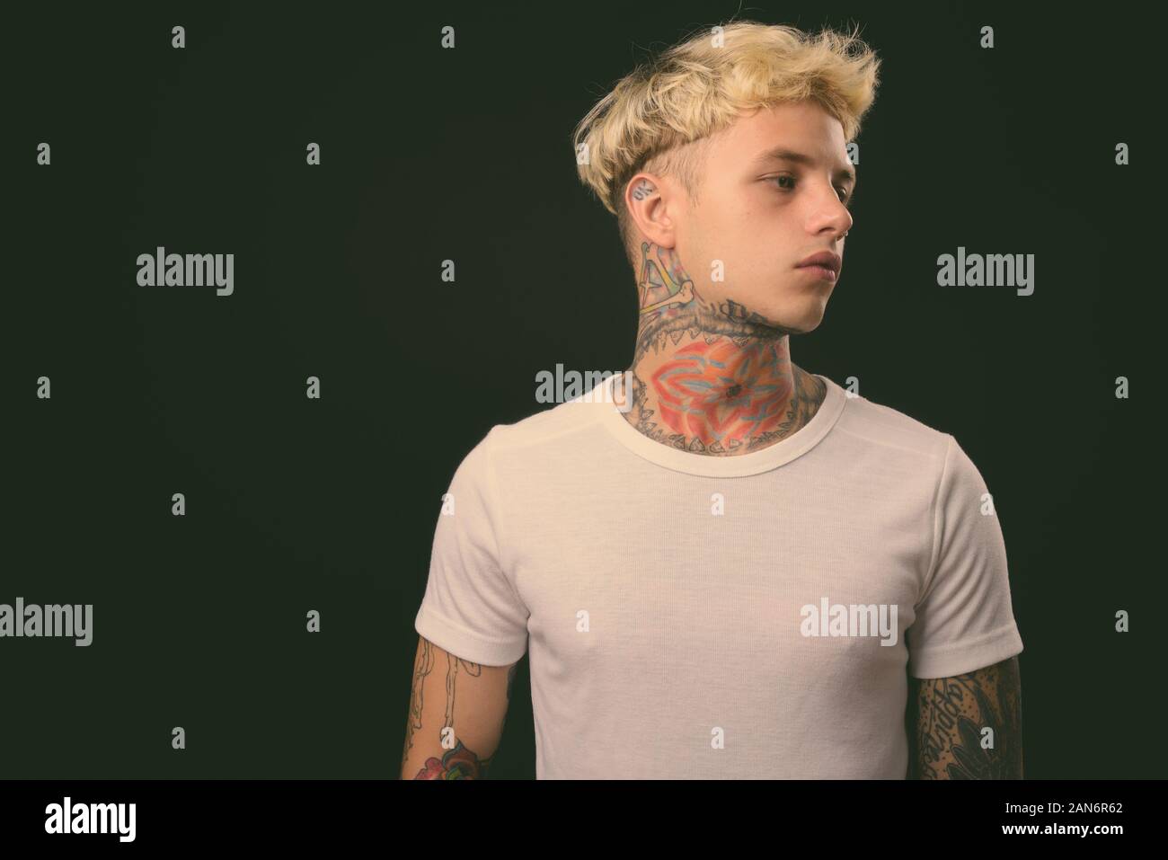 Beau jeune homme rebelle aux cheveux blonds sur fond noir Banque D'Images