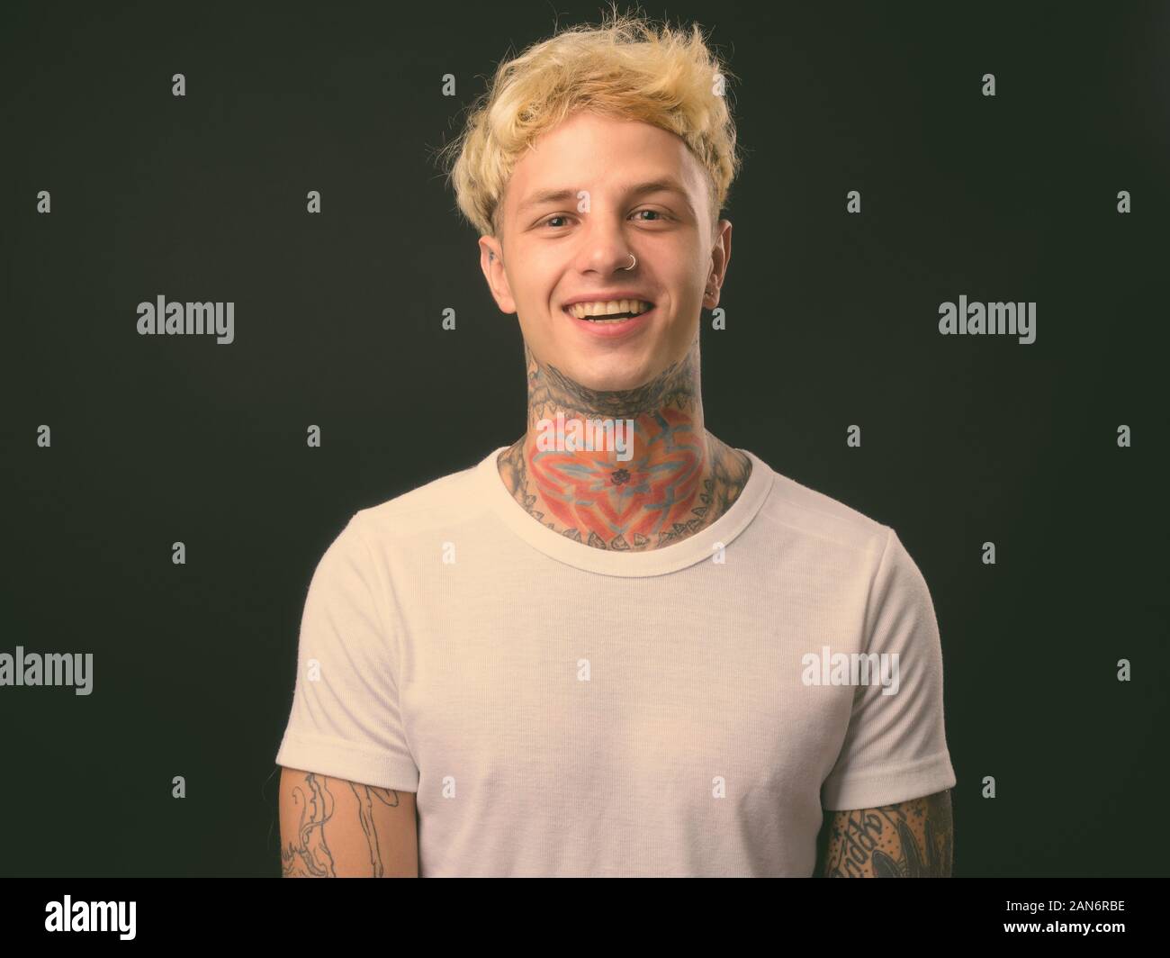 Beau jeune homme rebelle aux cheveux blonds sur fond noir Banque D'Images