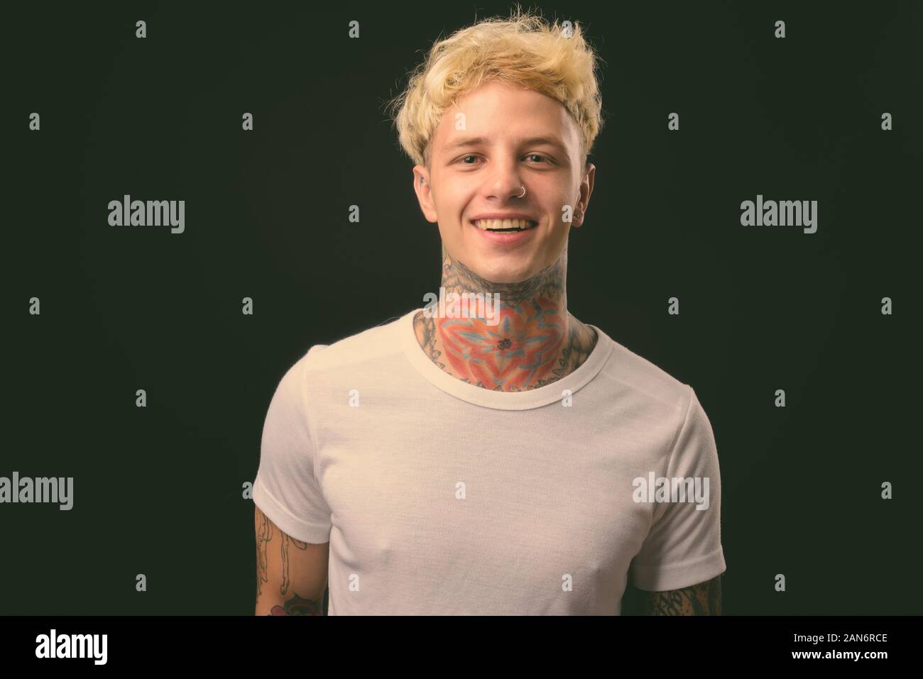 Beau jeune homme rebelle aux cheveux blonds sur fond noir Banque D'Images