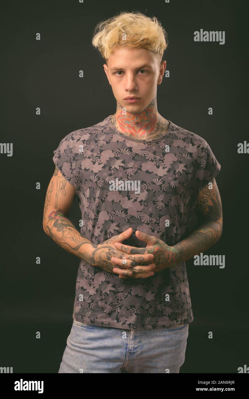 Beau jeune homme rebelle aux cheveux blonds sur fond noir Banque D'Images