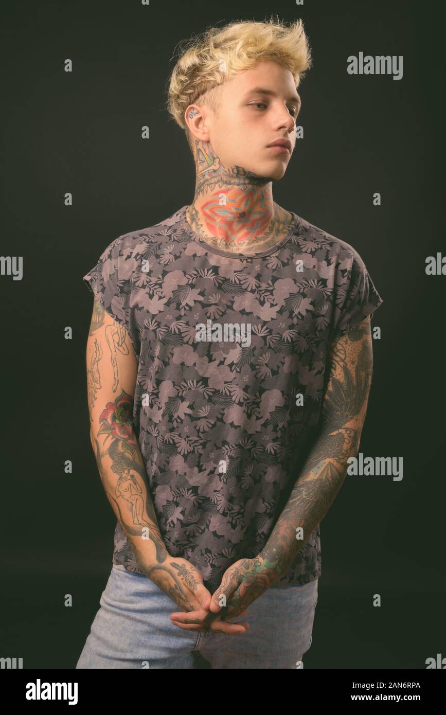 Beau jeune homme rebelle aux cheveux blonds sur fond noir Banque D'Images