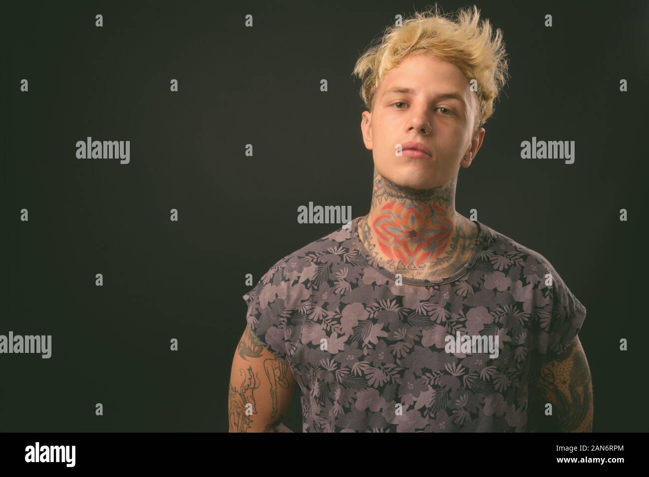 Beau jeune homme rebelle aux cheveux blonds sur fond noir Banque D'Images
