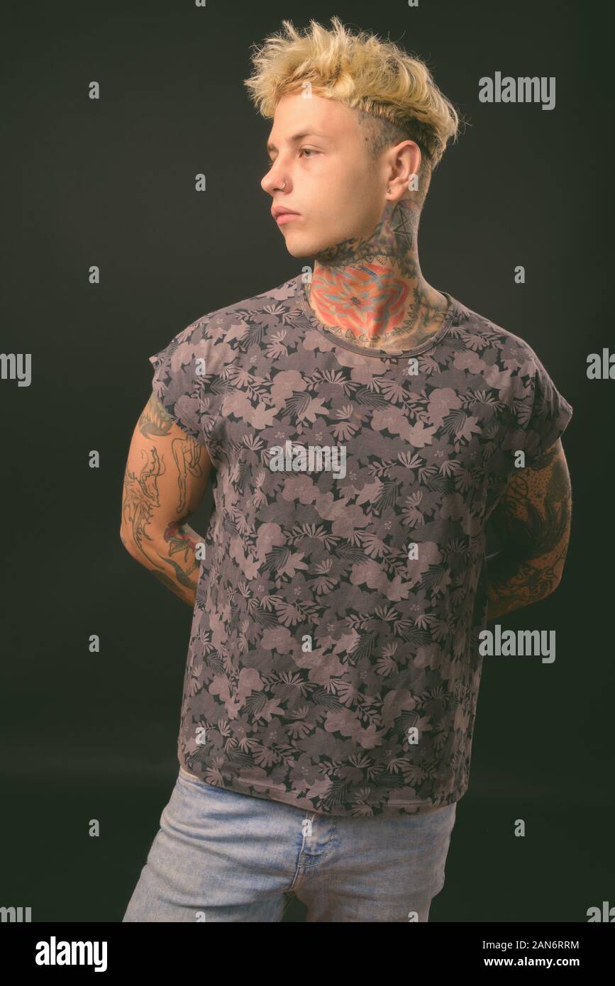 Beau jeune homme rebelle aux cheveux blonds sur fond noir Banque D'Images