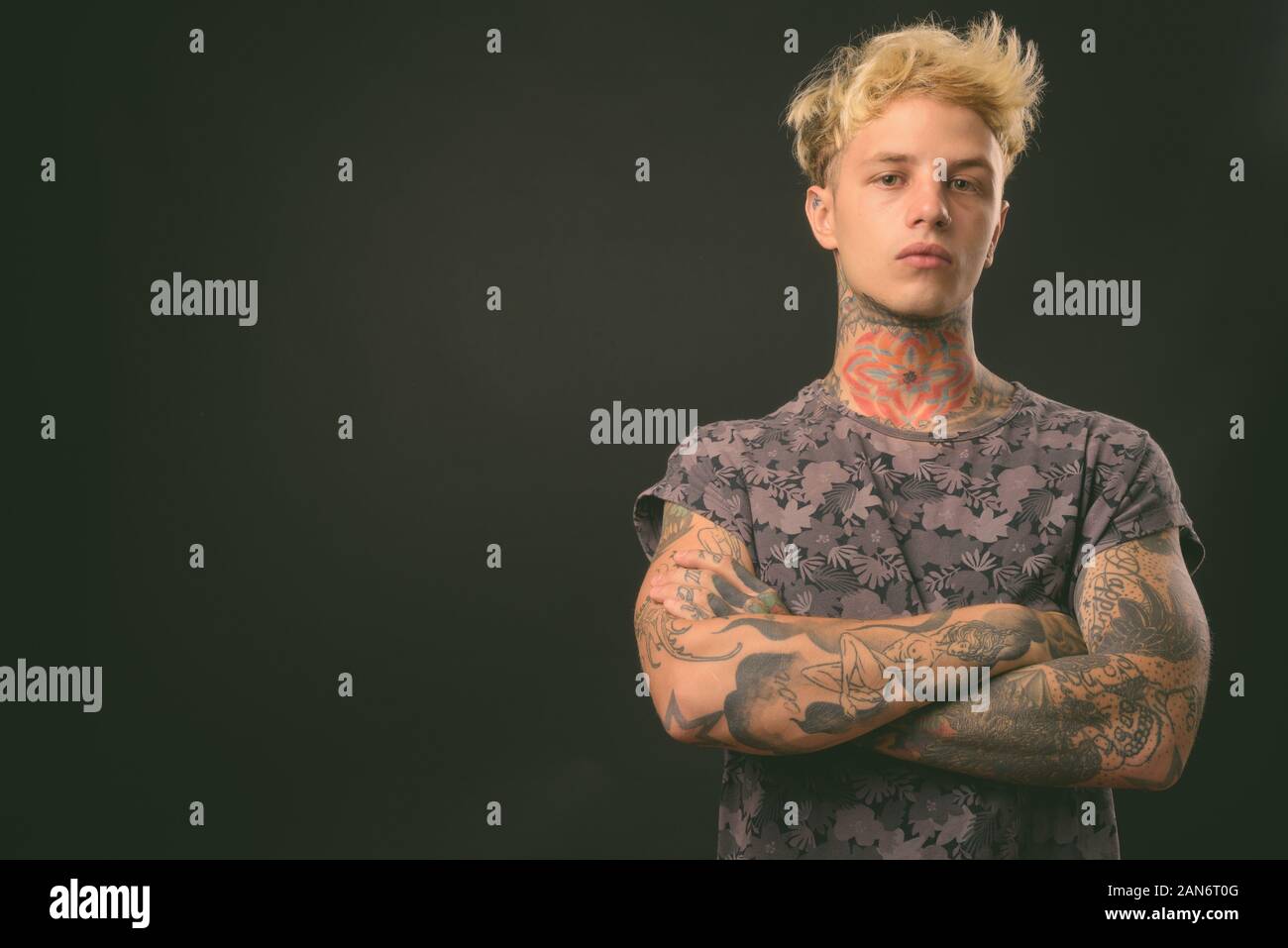 Beau jeune homme rebelle aux cheveux blonds sur fond noir Banque D'Images