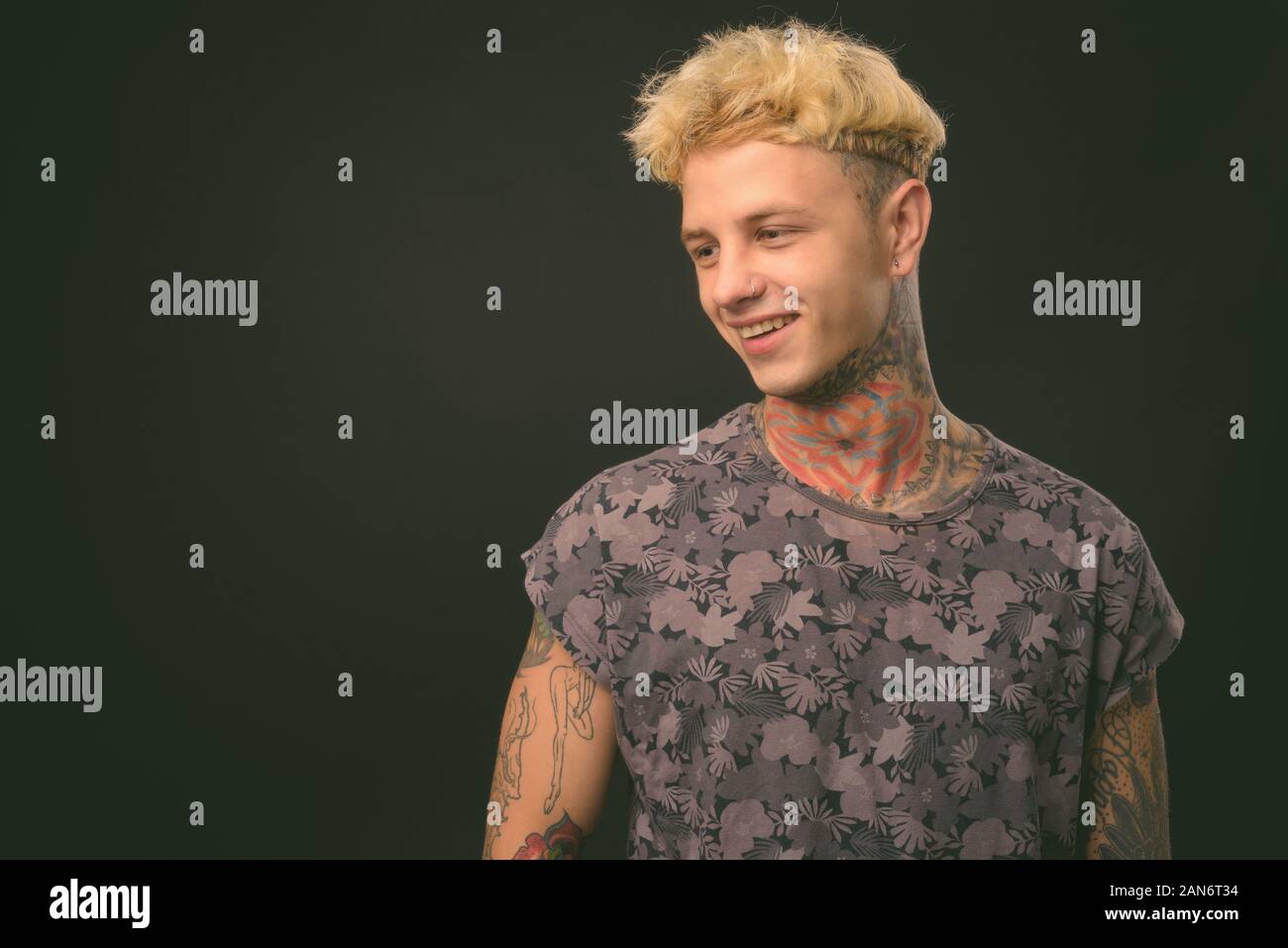 Beau jeune homme rebelle aux cheveux blonds sur fond noir Banque D'Images