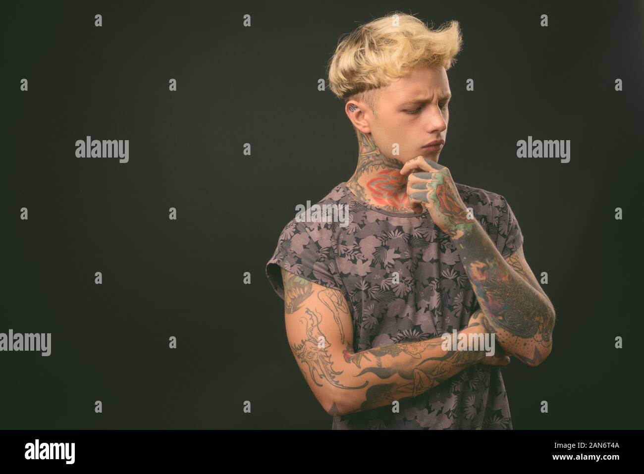 Beau jeune homme rebelle aux cheveux blonds sur fond noir Banque D'Images