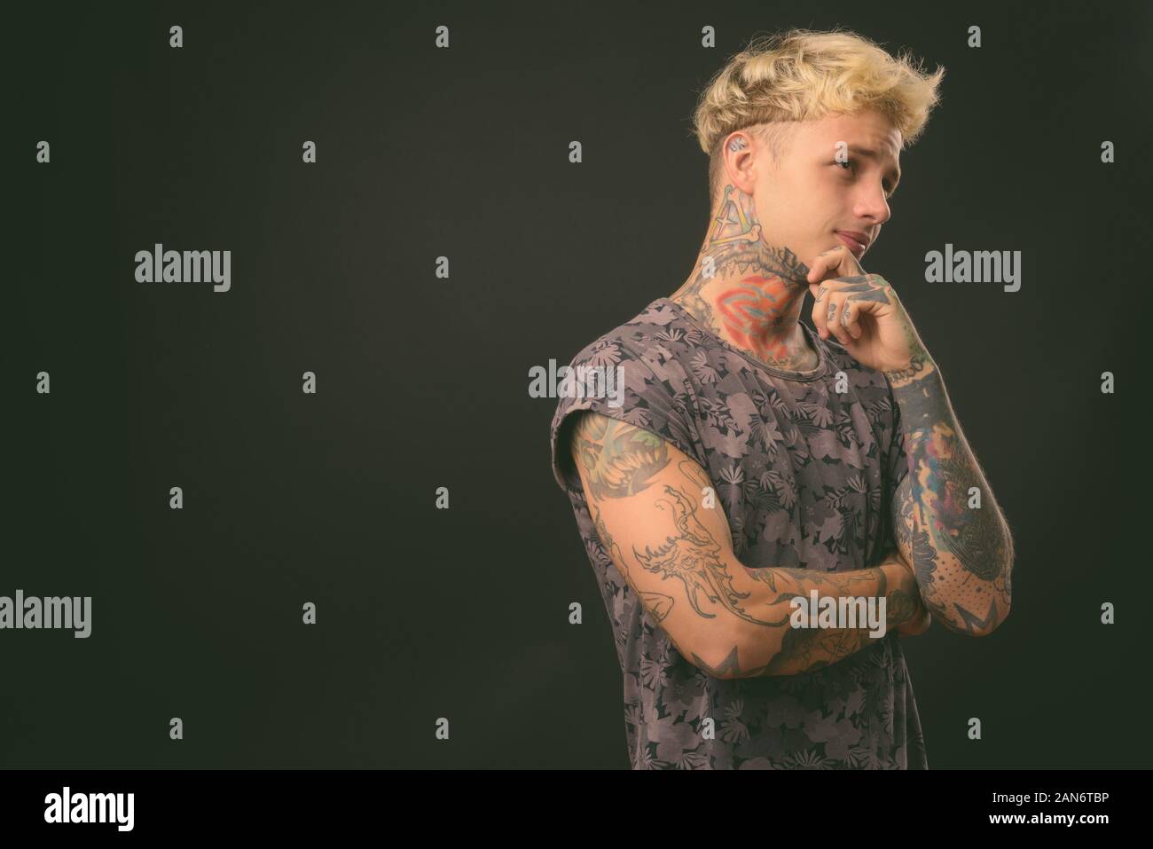 Beau jeune homme rebelle aux cheveux blonds sur fond noir Banque D'Images
