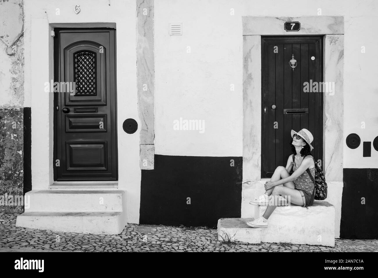Woman sitting dans les rues d'un village dans la région de l'Alentejo du Portugal en noir et blanc Banque D'Images