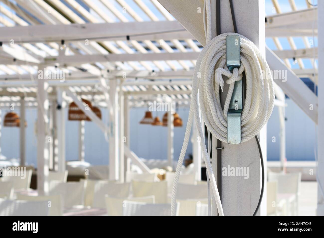 Une corde blanche accrochée sur les piliers d'une terrasse de plage unifiée en blanc massif dans un complexe d'été Banque D'Images