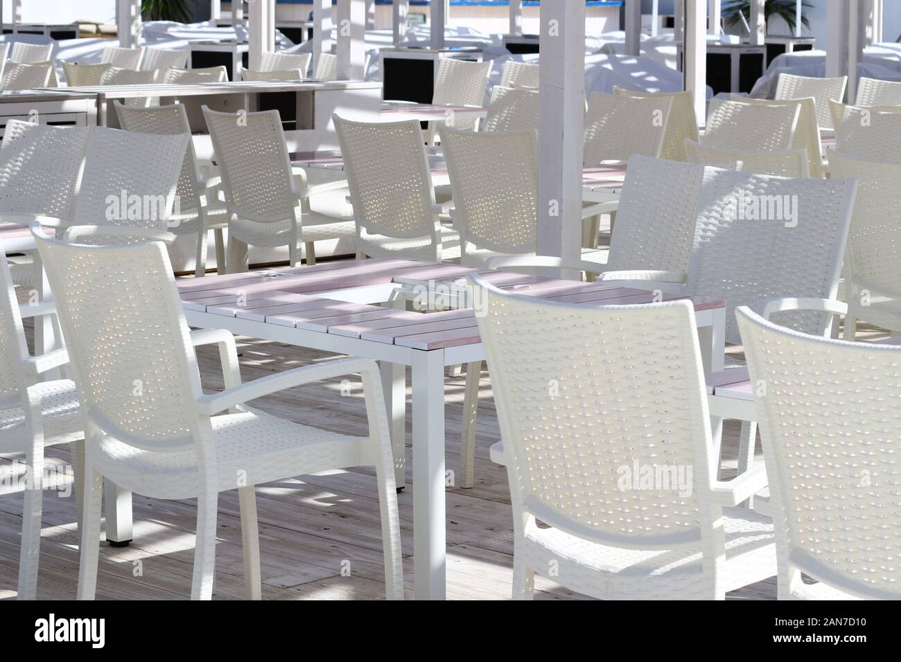Il y a plein de tables et de chaises blanches disposées sur une terrasse de plage unifiée en blanc dans un complexe hôtelier d'été Banque D'Images