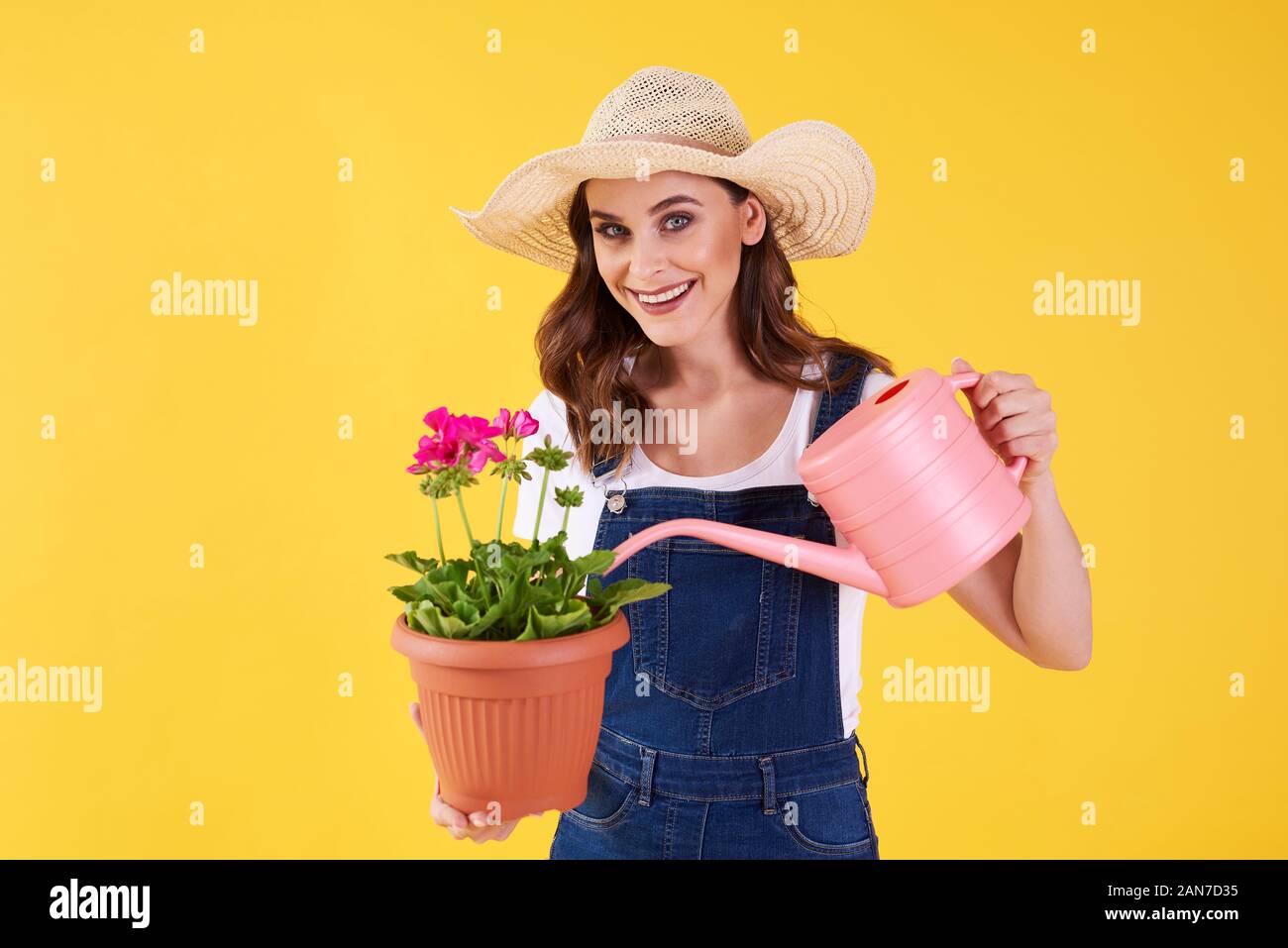 Smiling woman arroser la fleur dans le studio shot Banque D'Images