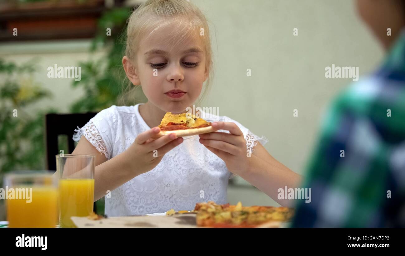 Preschool girl eating pizza italien préféré, profitant de savoureux repas, livraison de nourriture Banque D'Images