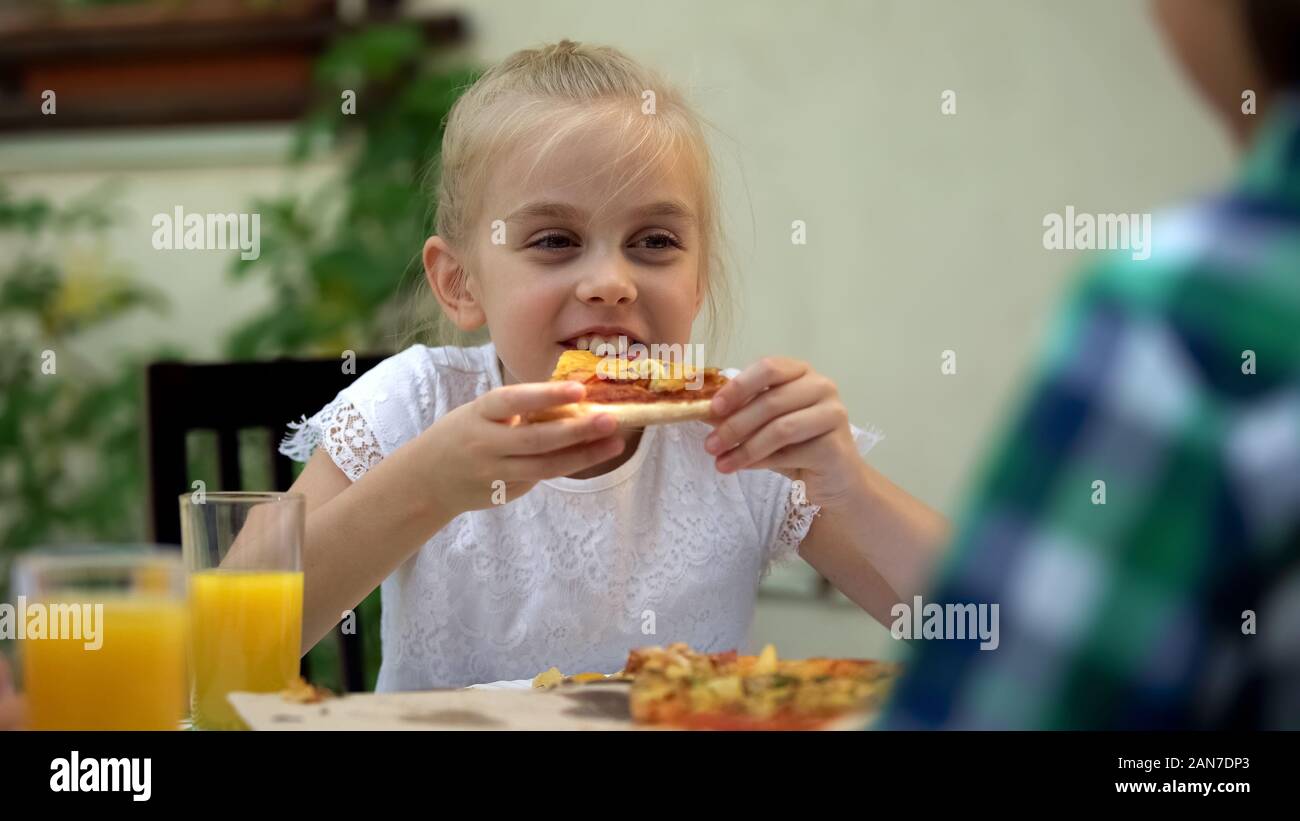 Girl eating pizza avec frère dans cafe, celebrating birthday, nourriture de favori Banque D'Images