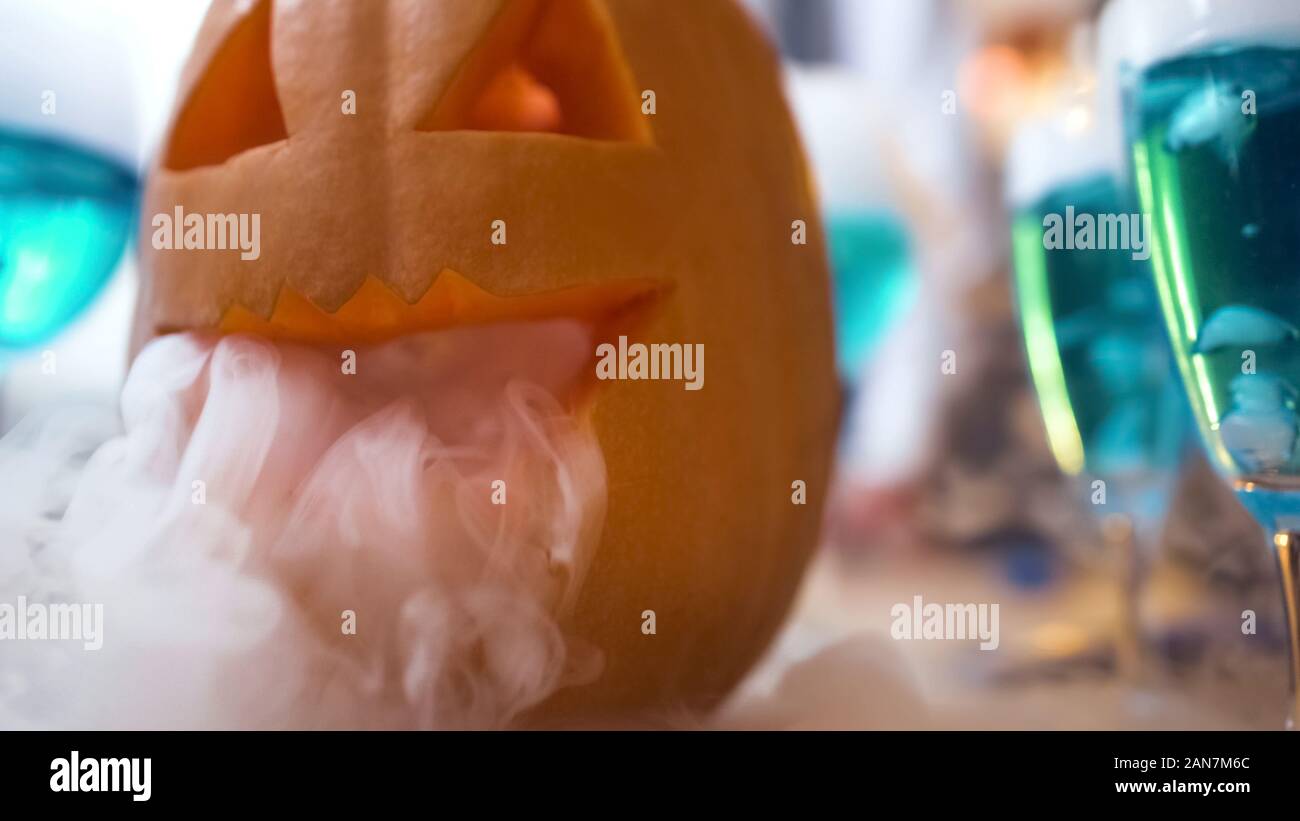 Jack lantern fumeurs sculpté, bleu des cocktails sur Halloween party table, close-up Banque D'Images