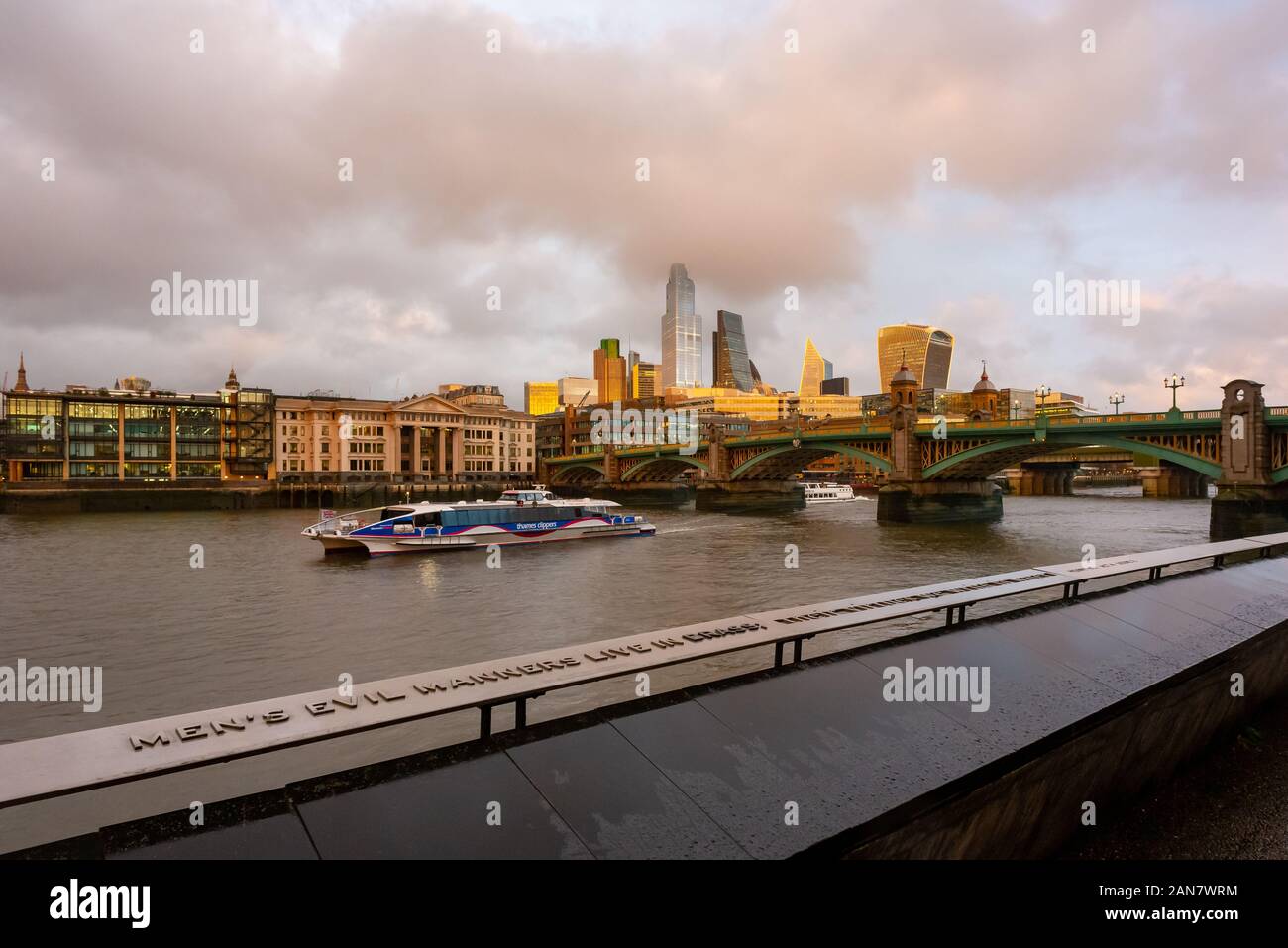 Garde-corps gravé sur la rive sud de la Tamise à Southwalk pont avec la ville de Londres illuminée en soleil doré à l'arrière-plan Banque D'Images