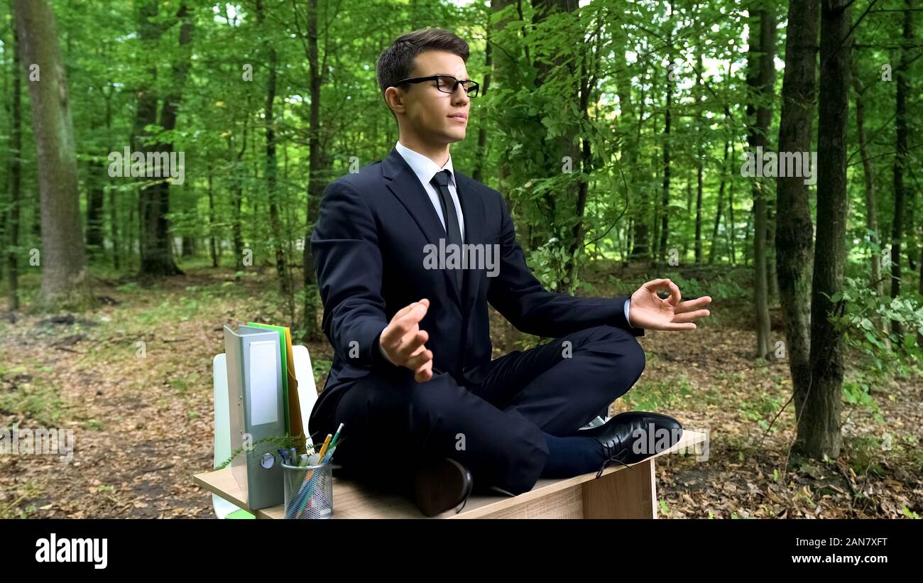 Homme d'affaires décontractée méditant dans la position du lotus à l'extérieur, soulagement du stress au travail Banque D'Images