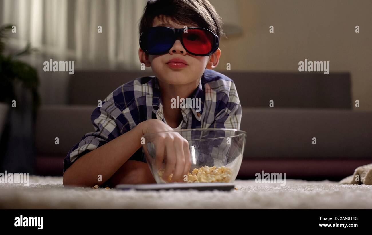 Petit garçon à regarder des films en 3D sans lunettes et eating popcorn,  bénéficiant à la maison Photo Stock - Alamy