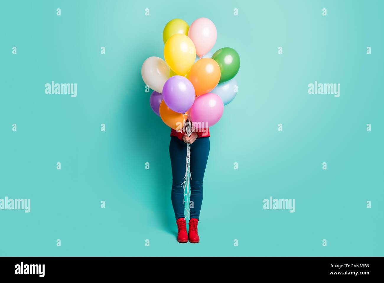 Guess Who. Photo de pleine longueur dame masquée détenant plusieurs ballons colorés rendre visite surprise porter des bottes Pantalons décontractés manteau rouge sarcelle isolés Banque D'Images