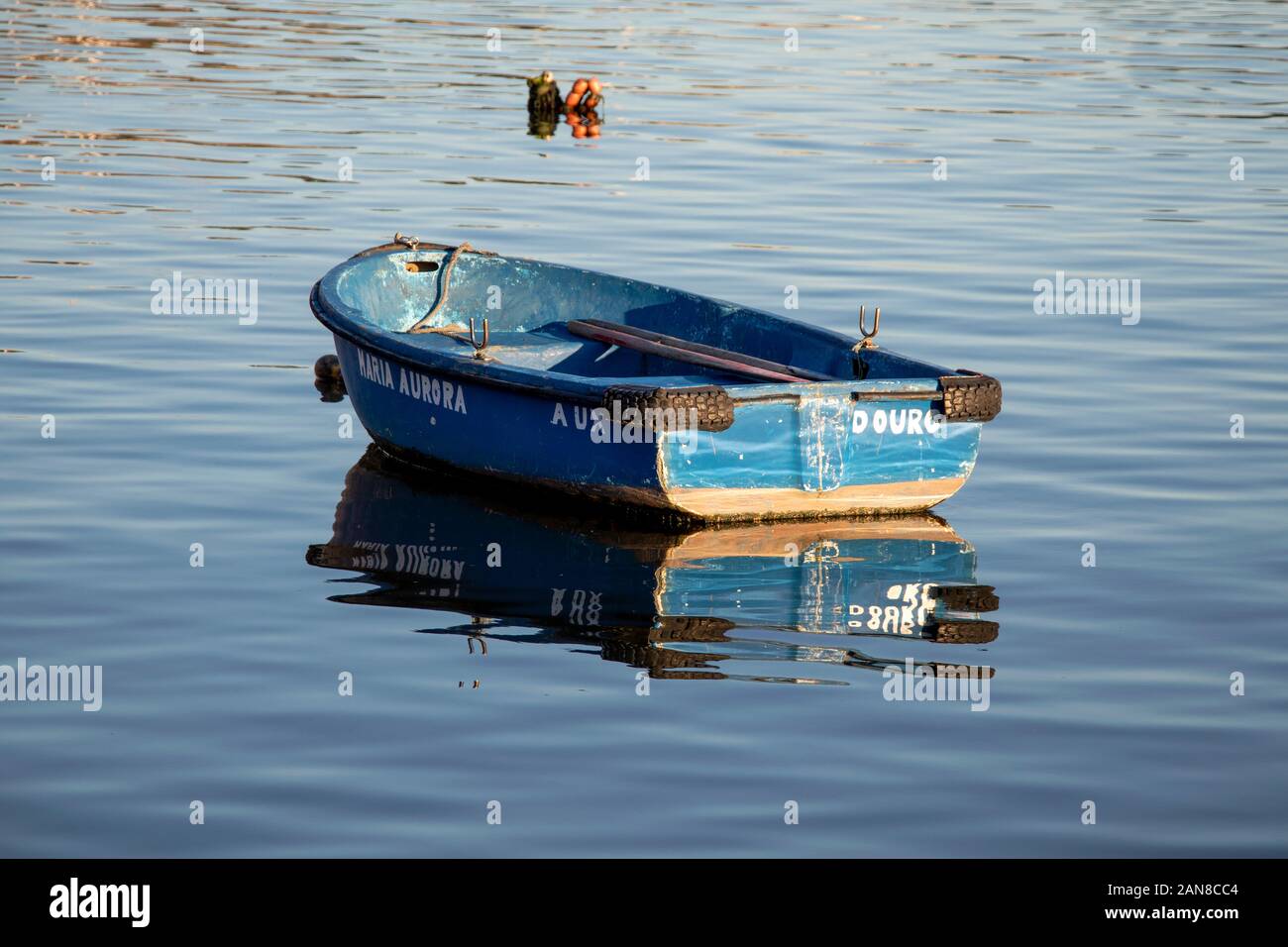 Bateau à rames en bois bleu flottant sur l'eau calme avec reflets Banque D'Images