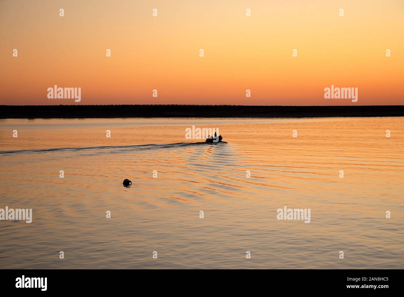 Pêcheurs en bateau à ramer au coucher du soleil dans l'estuaire du fleuve Douro, Porto, Portugal. Banque D'Images