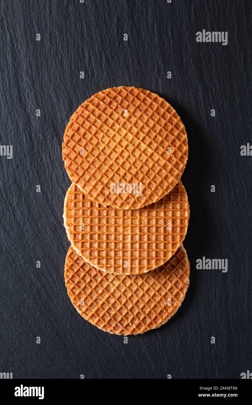 Concept alimentaire Stroopwafel, croustillant de sirop de caramel gaufres néerlandaise sur fond noir en ardoise noire Banque D'Images