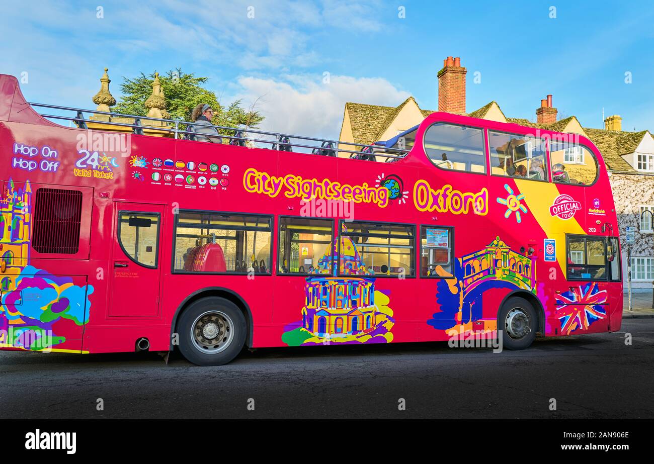Hop-on hop-off open top ville double decker bus voir peint avec des couleurs criardes en dehors de Trinity College à l'université d'Oxford, en Angleterre. Banque D'Images