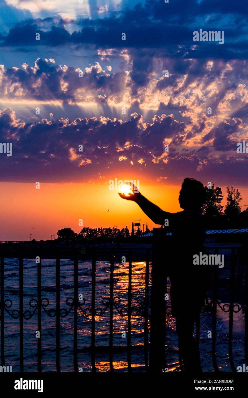 Silhouette de femme. Une femme à prendre le soleil par les mains sur un  fond lumineux nuageux coucher du soleil. La photographie de la mer d'été en  Ukraine Photo Stock - Alamy
