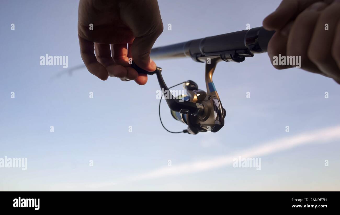 Mans hands spinning bobine de pêche, engins de capture du poisson, et de fournitures, Close up Banque D'Images