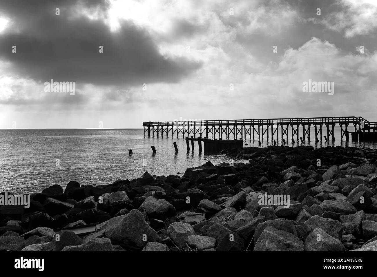 Noir et blanc rétroéclairé, silhouette d'un homme debout sur un quai de pêche sur un froid matin d'hiver dans la baie du Delaware. Banque D'Images