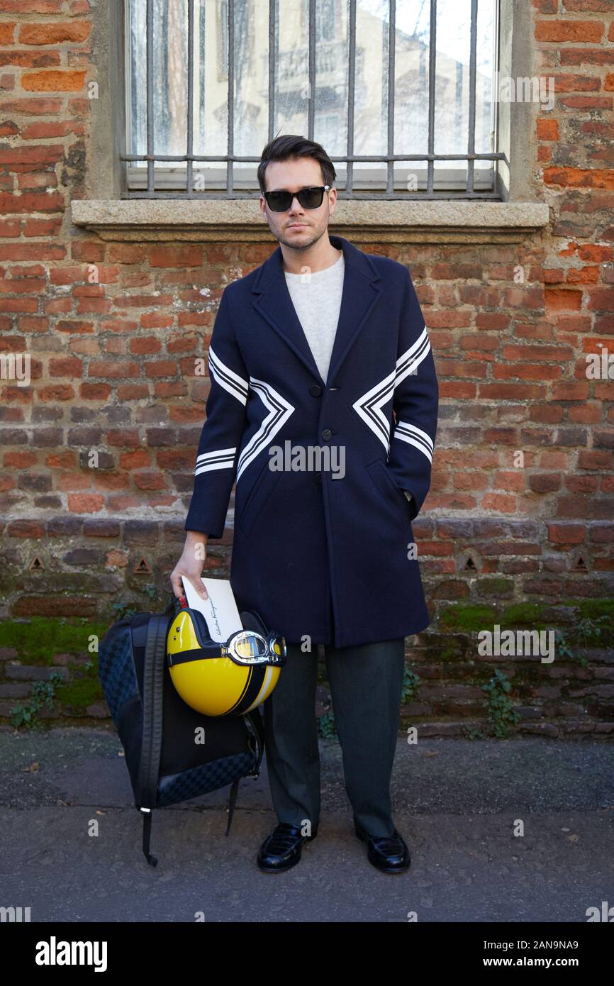 MILAN, ITALIE - 12 janvier 2019 : l'Homme avec casque jaune, sac et manteau bleu avant de Salvatore Ferragamo fashion show, Milan Fashion Week street sty Banque D'Images