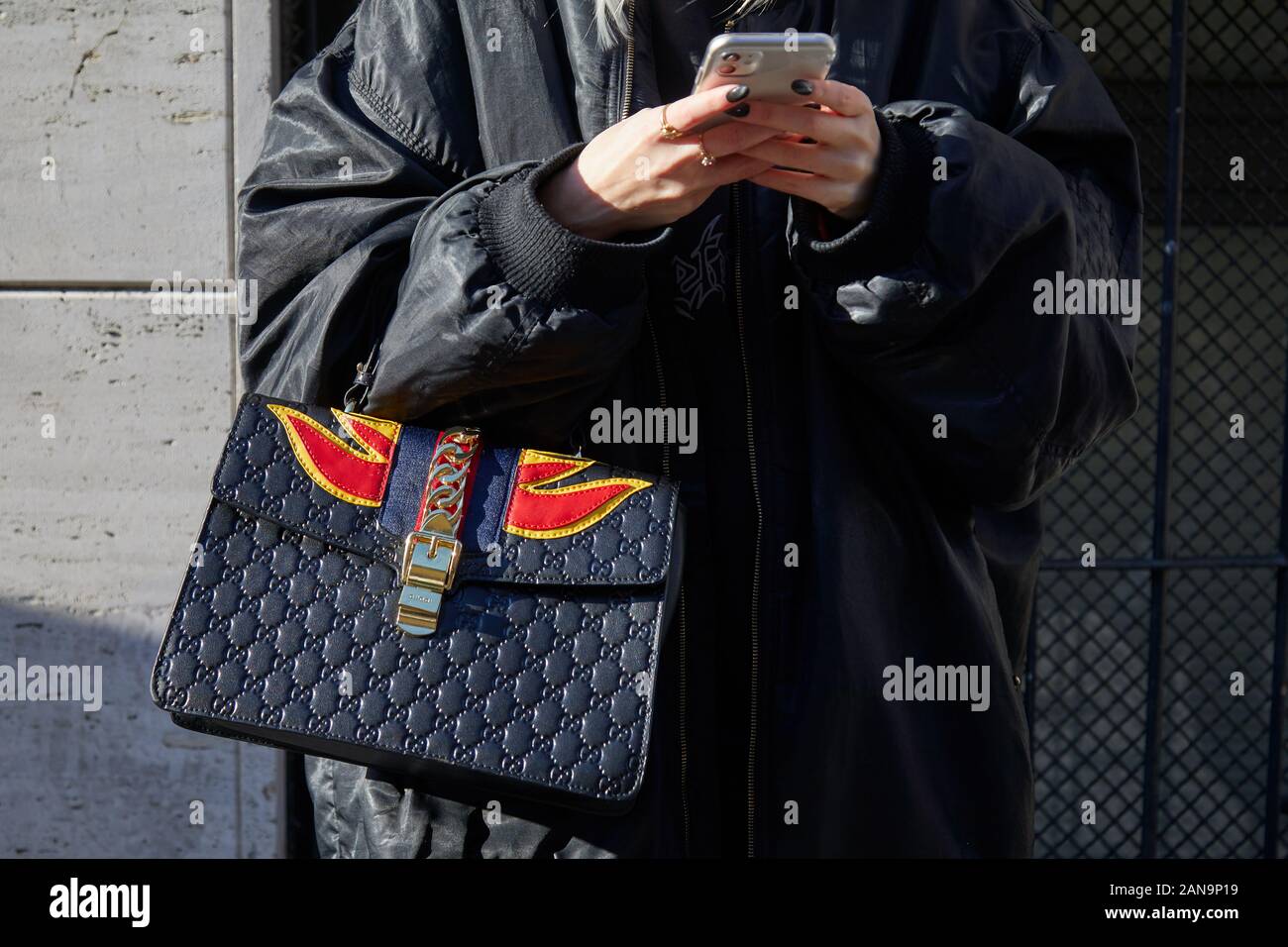 MILAN, ITALIE - 12 janvier 2019 : Femme avec Gucci Sac en cuir noir avec flammes rouges et jaunes, looking at smartphone avant le défilé Etro Milan, F Banque D'Images MILAN, ITALIE - 12 janvier 2019 : Femme avec Gucci Sac en cuir noir avec flammes rouges et jaunes, looking at smartphone avant le défilé Etro Milan, F Banque D'Images