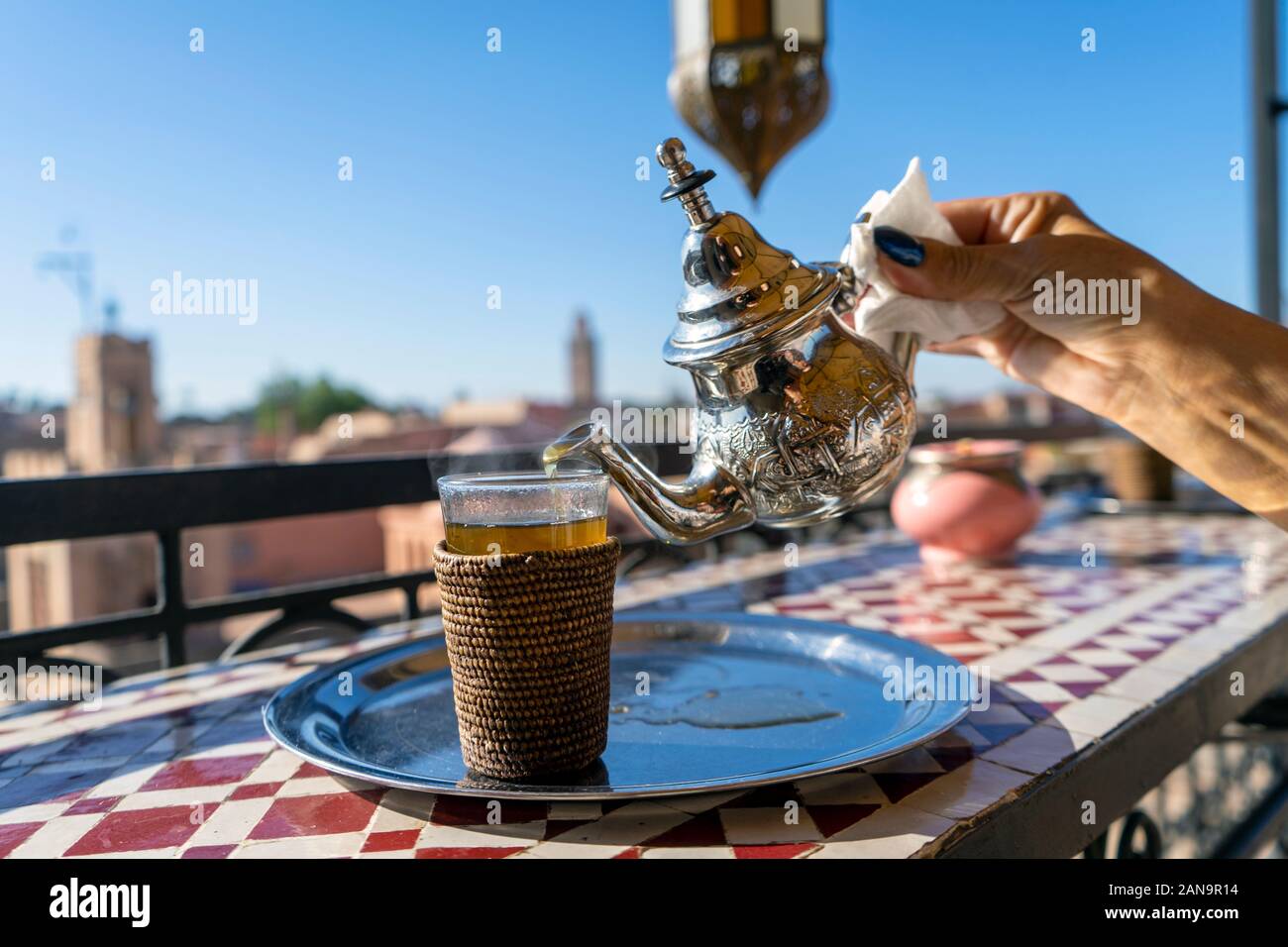 Verser le thé marocain de silver électrique pour le verre sur le toit haut de Marrakech, Maroc Banque D'Images