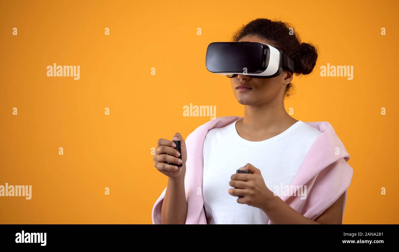 Afro-american woman in lunettes de réalité virtuelle jouer à des jeux, les contrôleurs de mouvement Banque D'Images