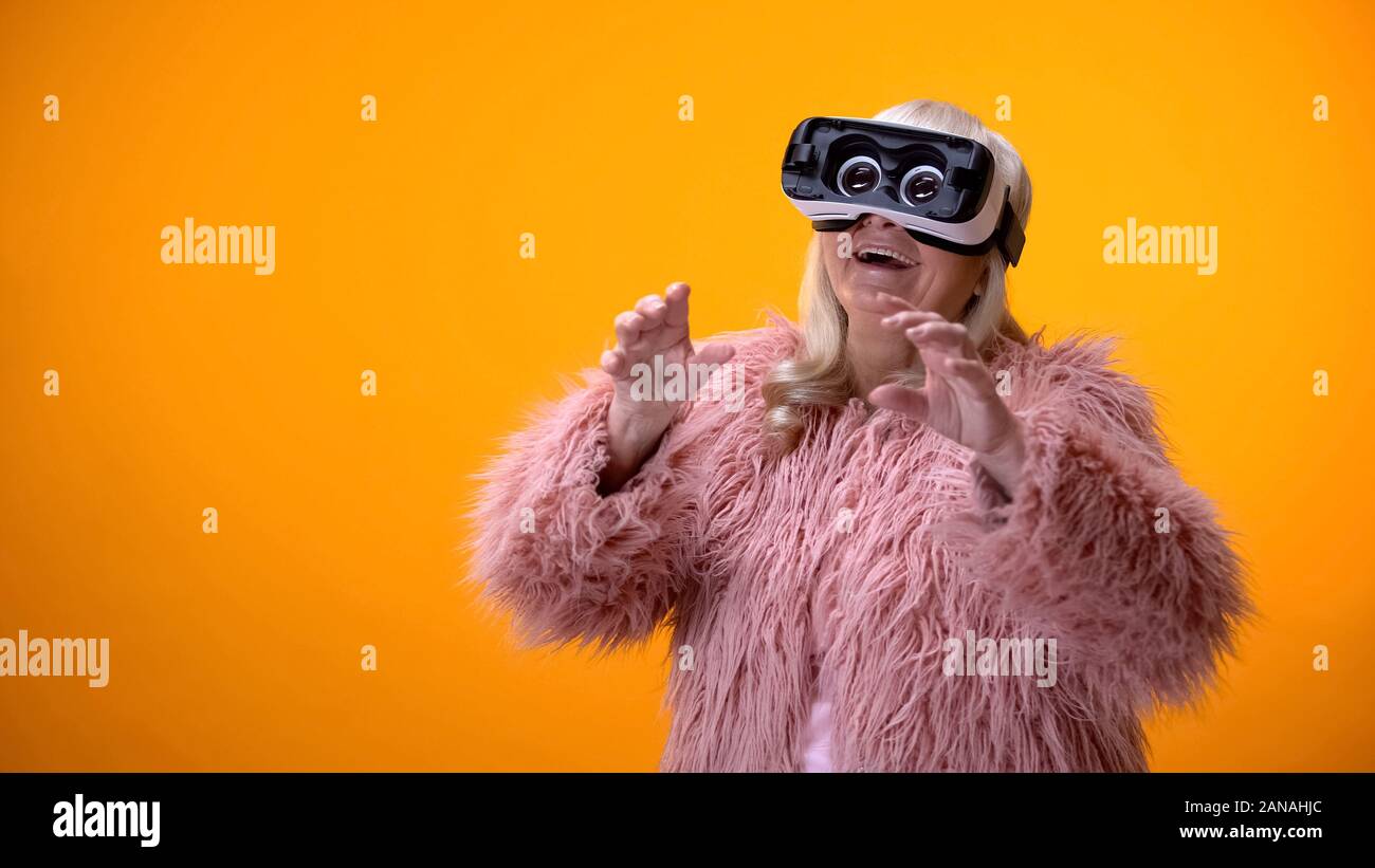 Senior woman in Positive et manteau rigolo casque VR jouant la technologie des jeux vidéo Banque D'Images