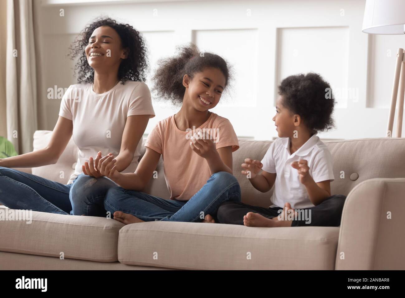 Cute black family having fun pendant les exercices de yoga à la maison. Banque D'Images