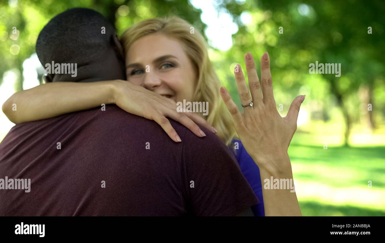 Cheerful woman embracing futur mari et montrant à l'occasion de fiançailles, couple Banque D'Images