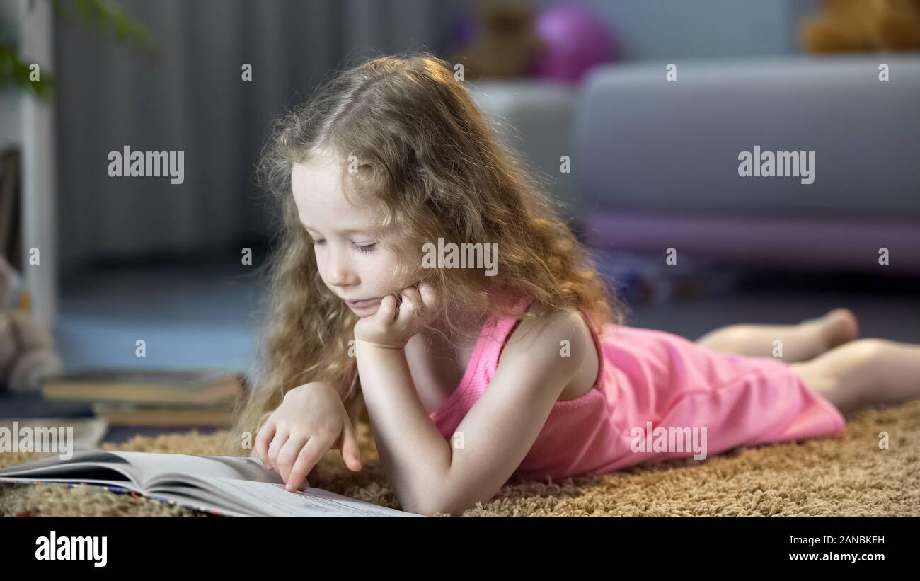 Petite fille intelligente lecture livre préféré à la maison, enfance heureuse, de l'éducation Banque D'Images