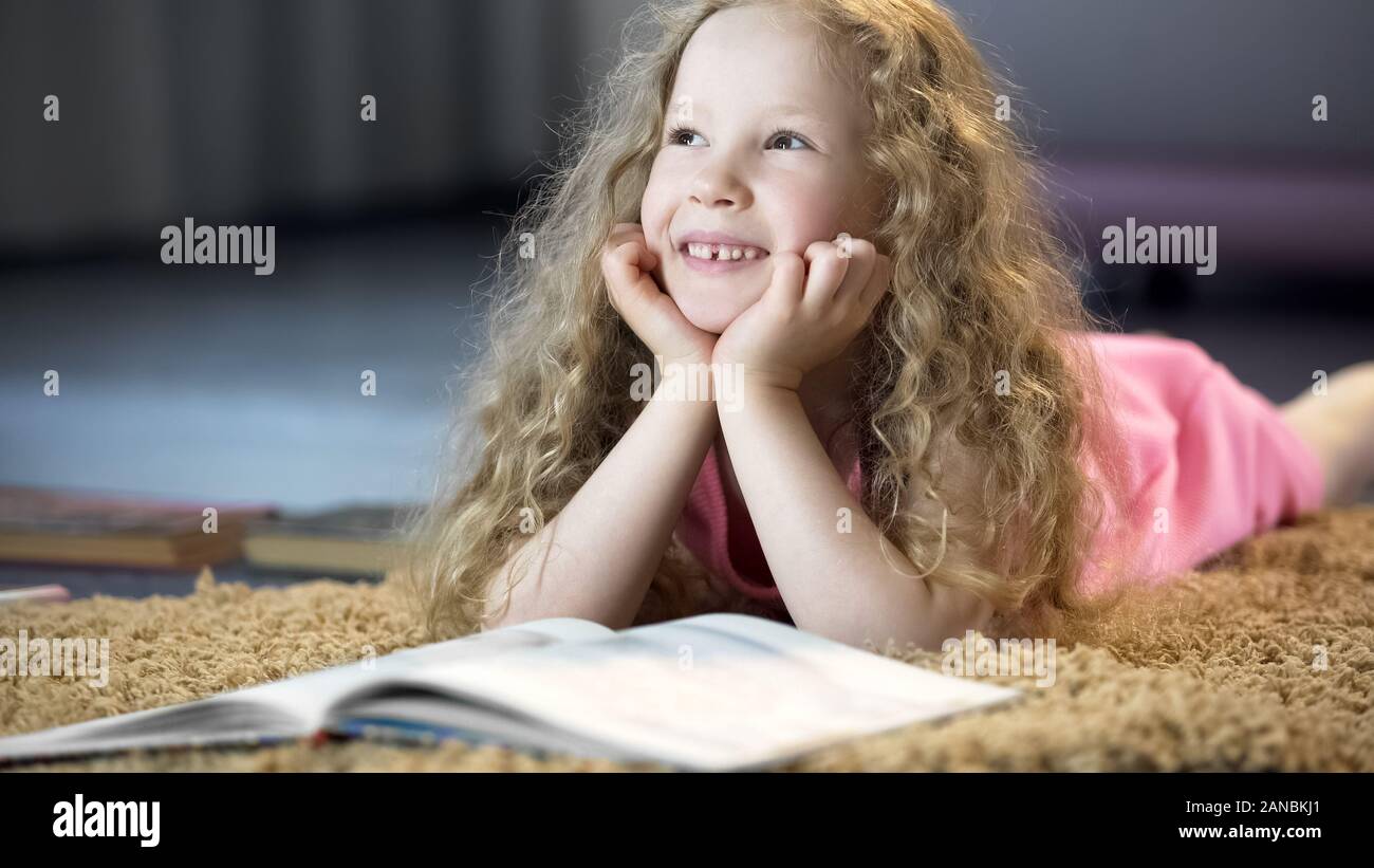 Cute young girl rêver d'avenir heureux, couché sur le tapis à la maison douce Banque D'Images